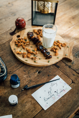 wooden plater with dates nuts and a glass of milk on wooden table with Ramadan Karem written on paper