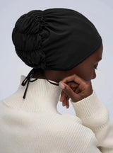 back of woman's head in black tie bonnet with cream turtleneck sweater 