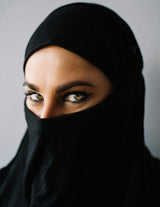 woman with hazel eyes with black niqab gray background